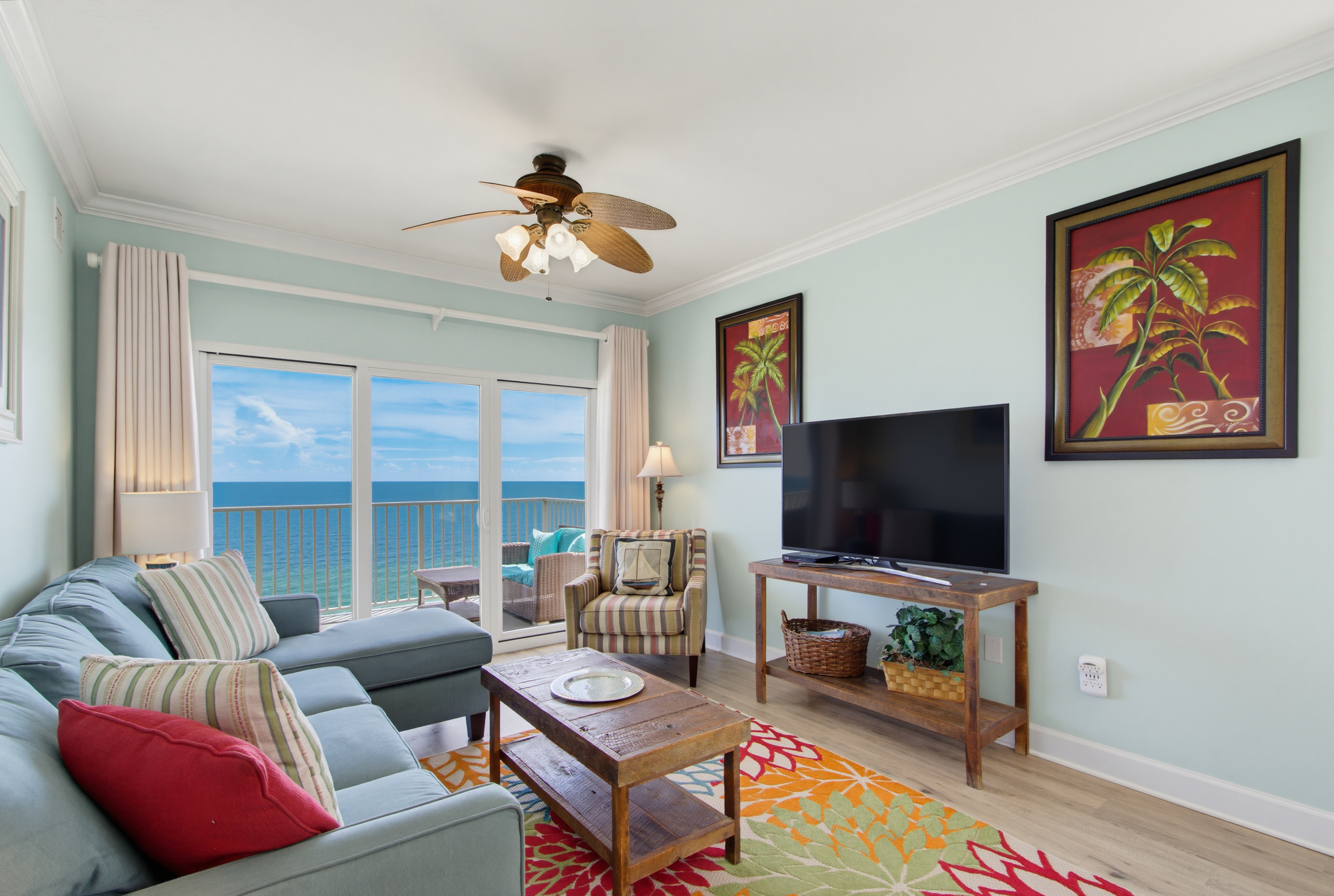 Living-area seating beside floor-to-ceiling Gulf views and a TV.
