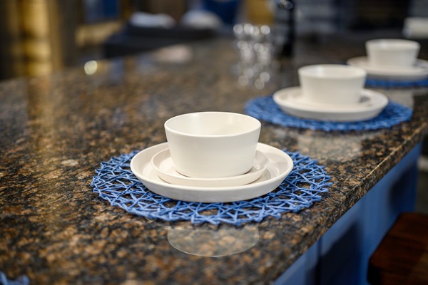 Elegant granite breakfast bar with designer seating and forest views.
