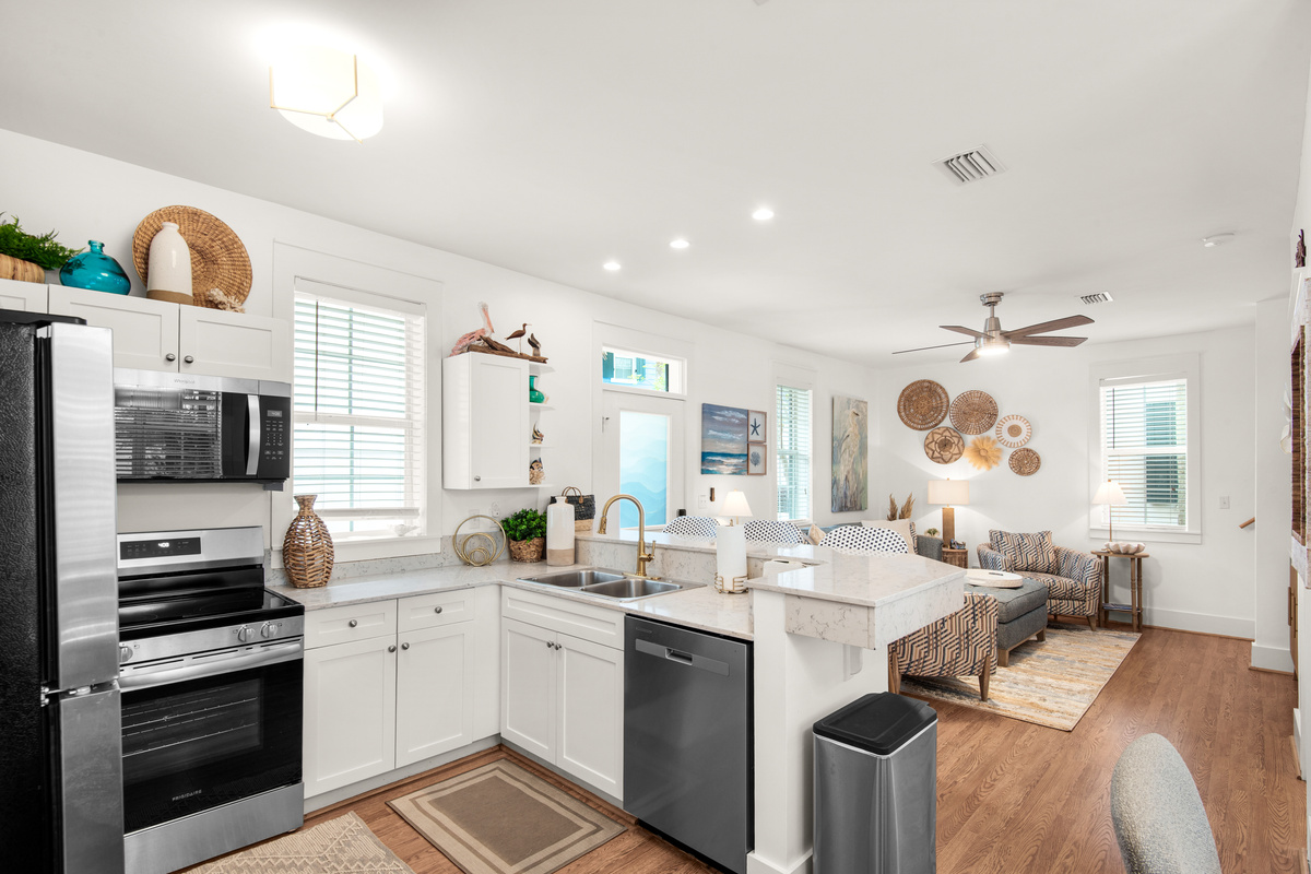 Open kitchen at Seagrove Bungalow 103 with an island, refrigerator and adjoining living area.