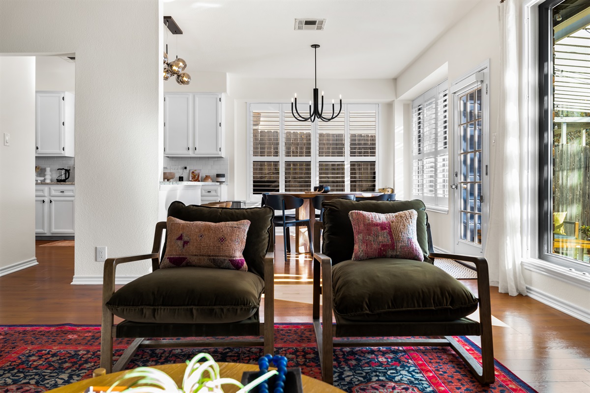 Living room's lounge seating with a kitchen backdrop.