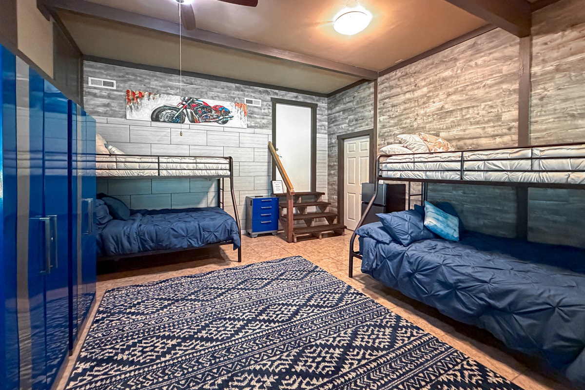 Spacious Downstairs Bunk Room featuring two bunk beds with full-size lower bunks and twin upper bunks, offering comfortable sleeping arrangements for up to 6 guests. A great space for kids, teens, or larger groups.