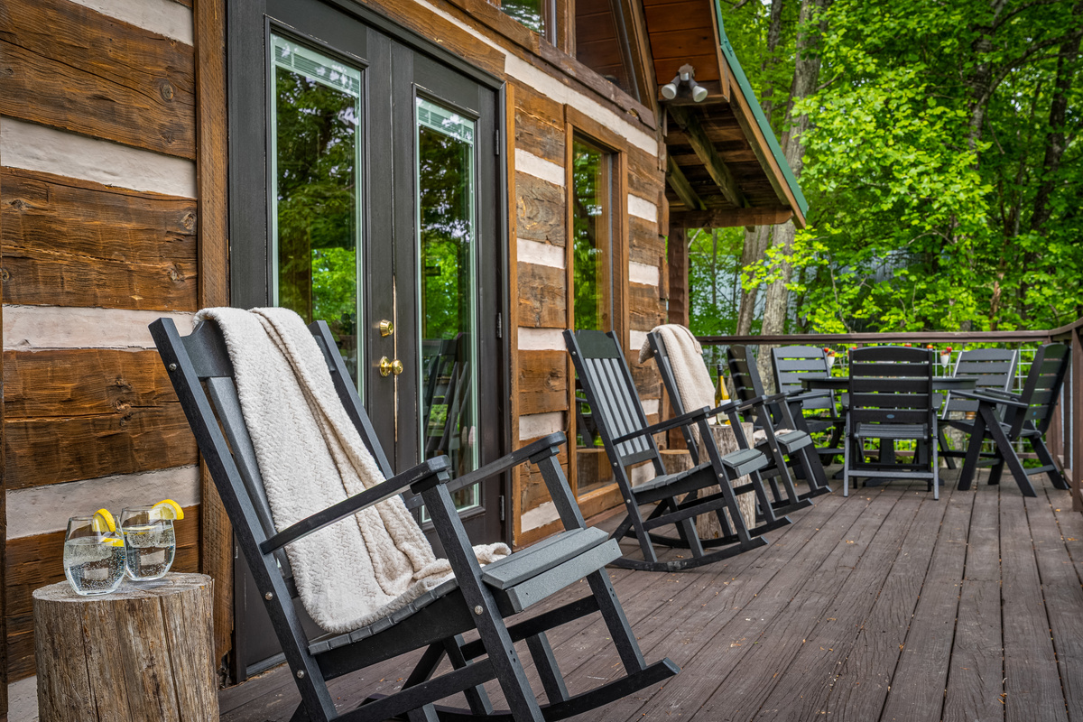 The main level deck has a variety of seating options, including rocking chairs and an outdoor dining table and chairs.