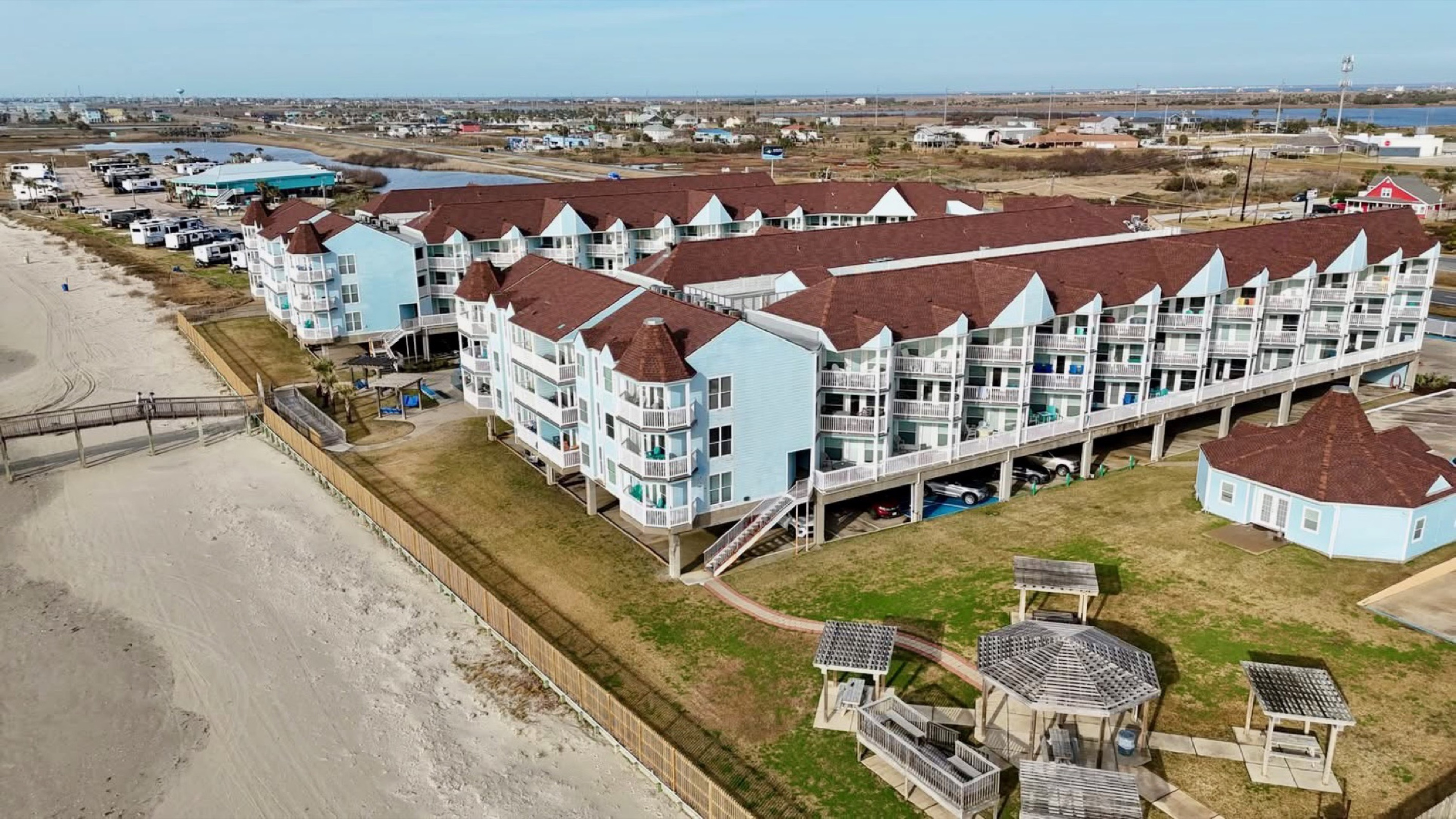 Grill and relax in the open-air dining area featuring pergolas, picnic tables, gazebos, and a raised platform with beach views—perfect for enjoying a meal or unwinding with your guests right by the sand within the gated resort.