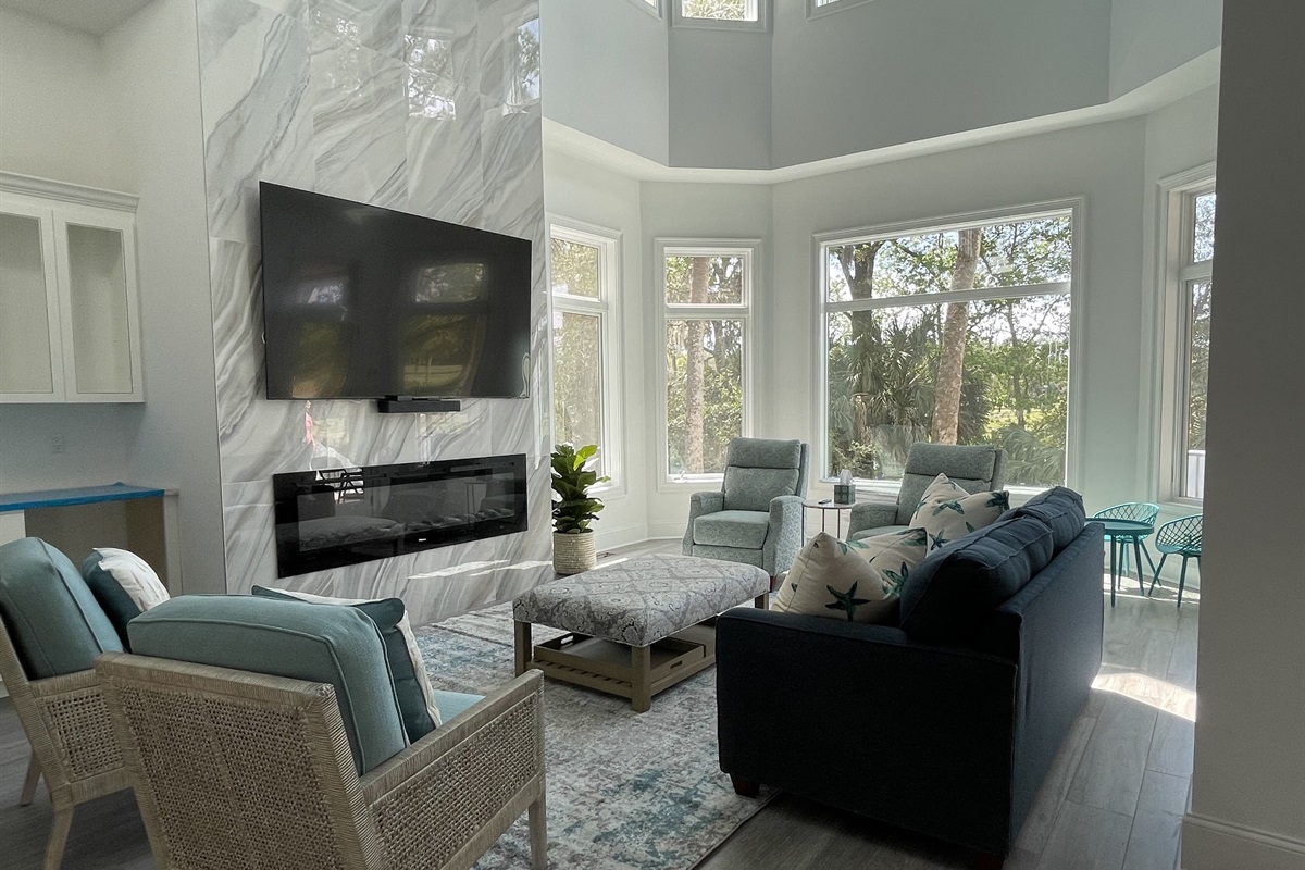 Living room has a 2 story fireplace wall with linear LED fireplace and wet bar