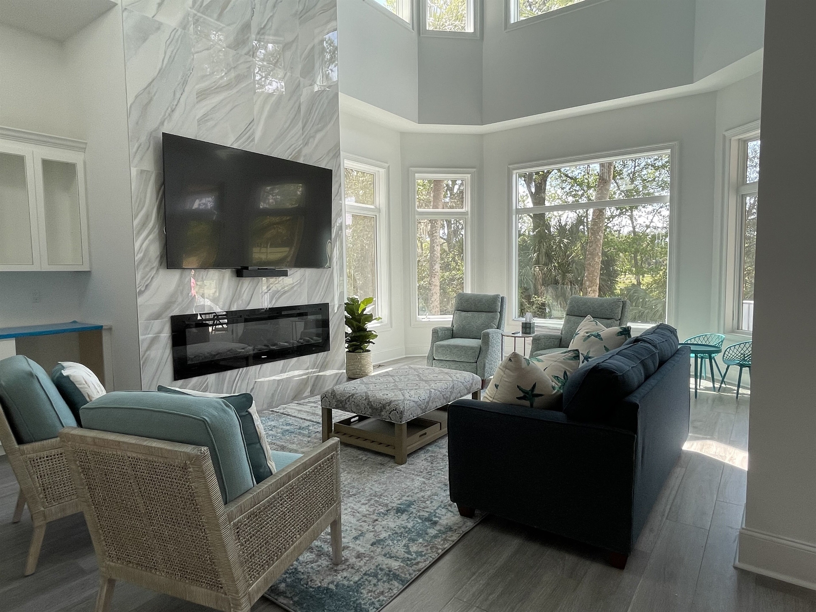 Living room has a 2 story fireplace wall with linear LED fireplace and wet bar