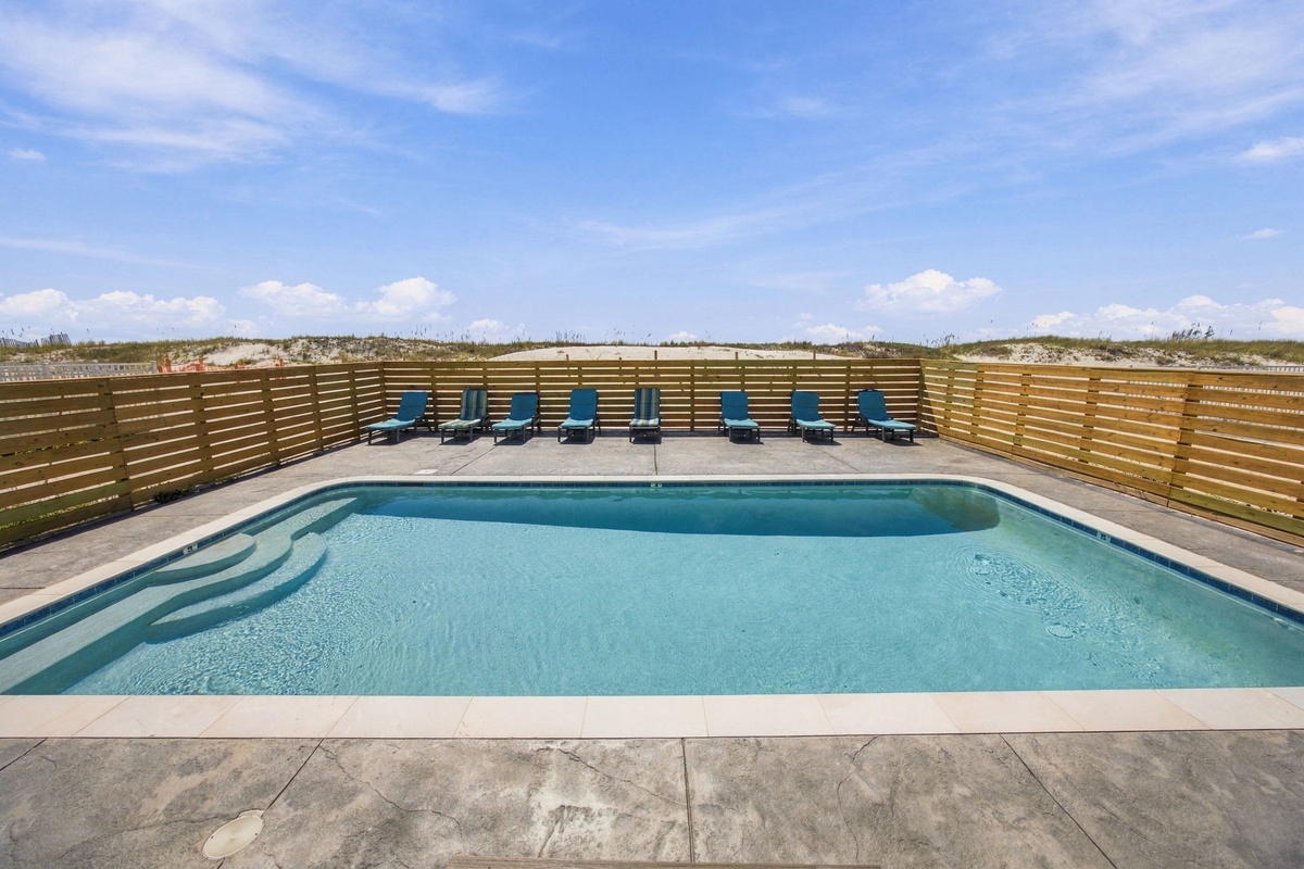 Shared swimming pool with lounge chairs and a spacious deck, offering a comfortable outdoor area for guests.