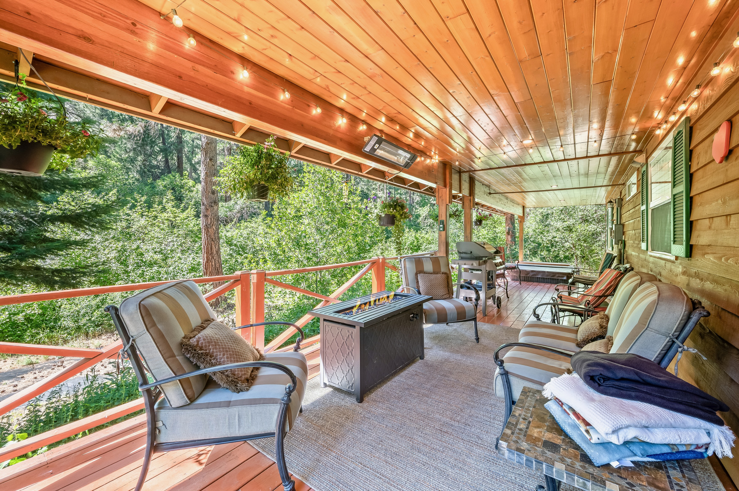 Large covered back porch includes seating, fire table, outdoor heater, BBQ and hot tub