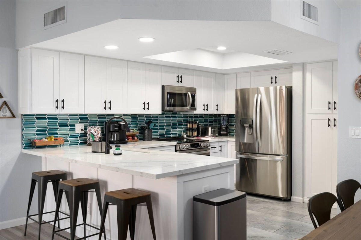 Completely remodeled kitchen boasts quartz countertops, beautiful teal glass backsplash, white shaker cabinets, stylish matte black faucet and cabinet pulls,  and all new LG appliances.