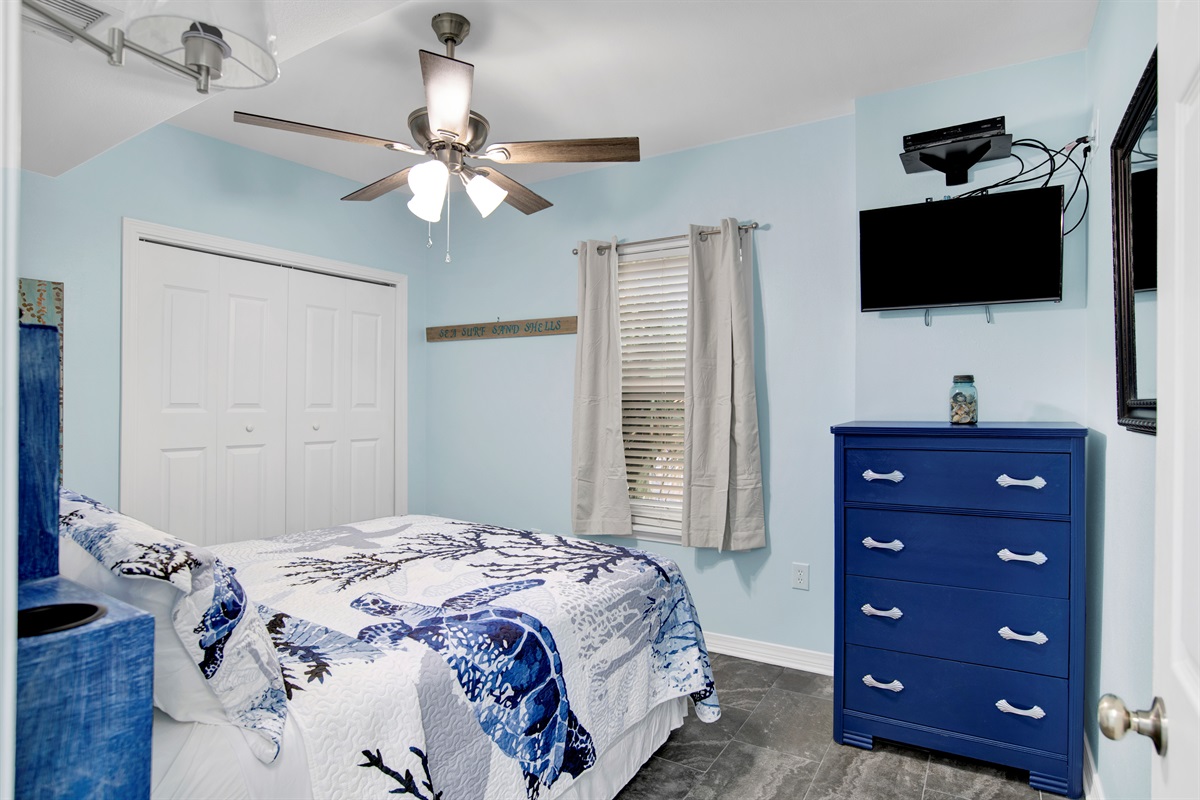 Bedroom 2 has a queen bed with built in side tables, ceiling fan, chest of drawers, and wall mounted smart TV