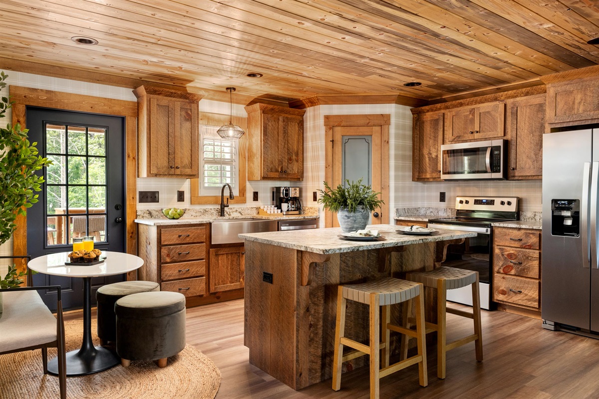 Gather around the oversized island, where high seating, wood cabinetry, and open space make every coffee, every meal, and every conversation feel effortless.