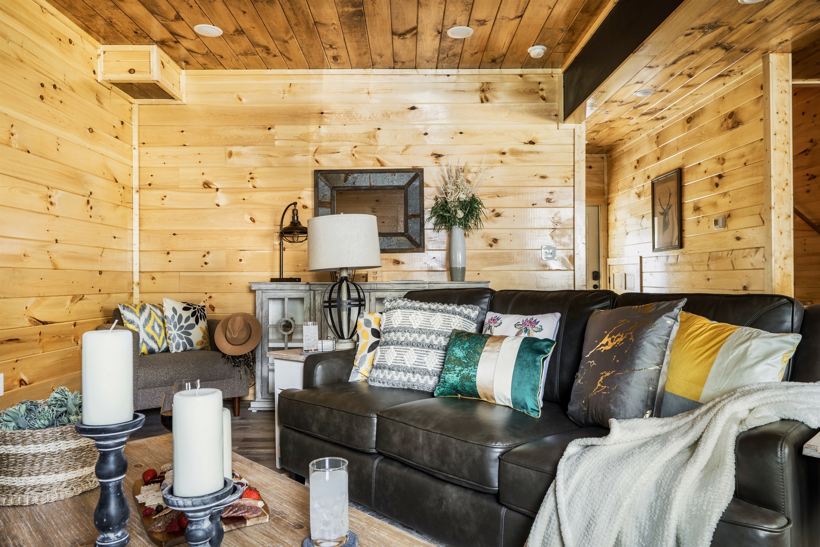 A luxurious living space featuring a spacious, comfortable couch, armchairs, and a 65-inch LED smart TV, surrounded by elegant decor.