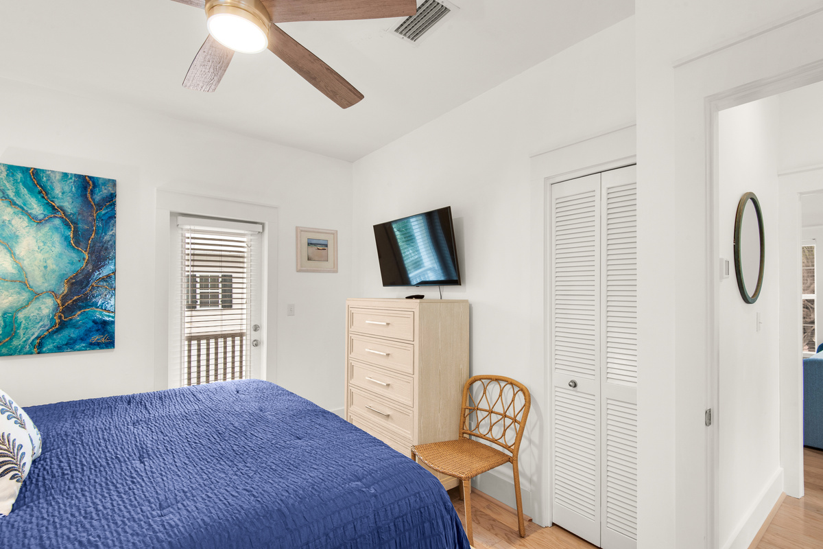 Seagrove Bungalow 103 bedroom with blue bedding, a dresser and wall-mounted television.