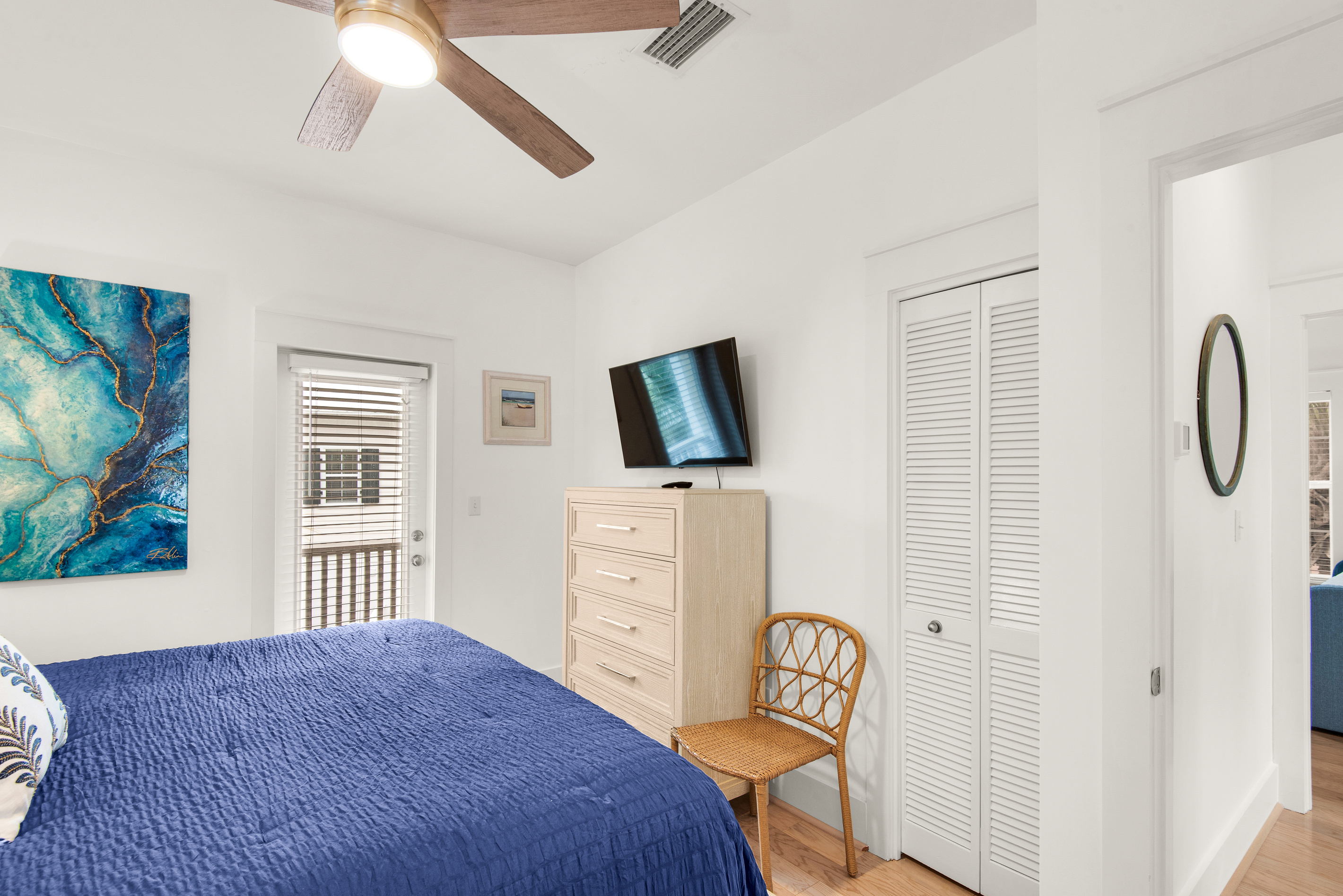 Seagrove Bungalow 103 bedroom with blue bedding, a dresser and wall-mounted television.