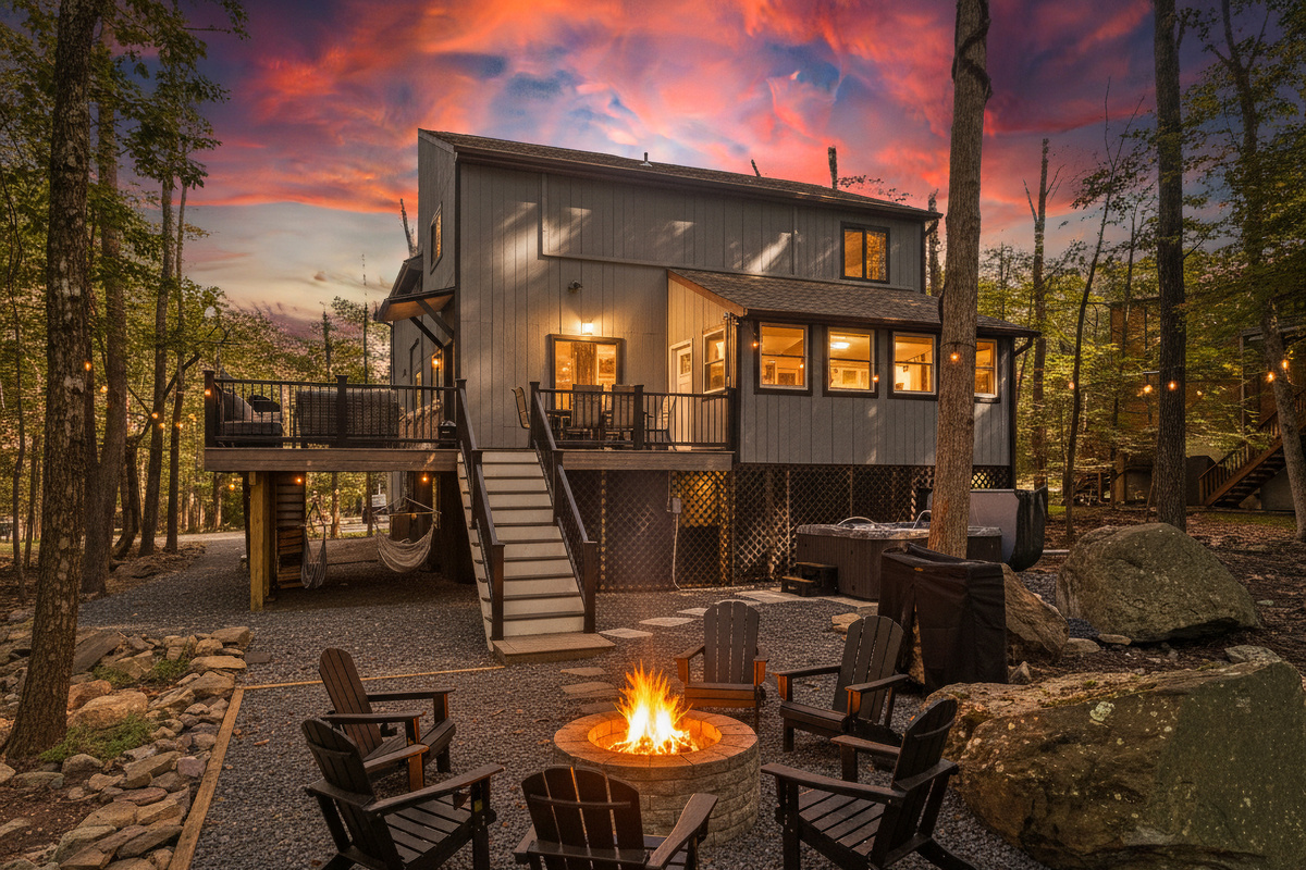 A private outdoor deck with dining space and a stone fire pit set against a wooded backdrop
