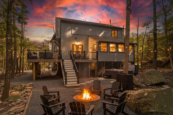  A private outdoor deck with dining space and a stone fire pit set against a wooded backdrop