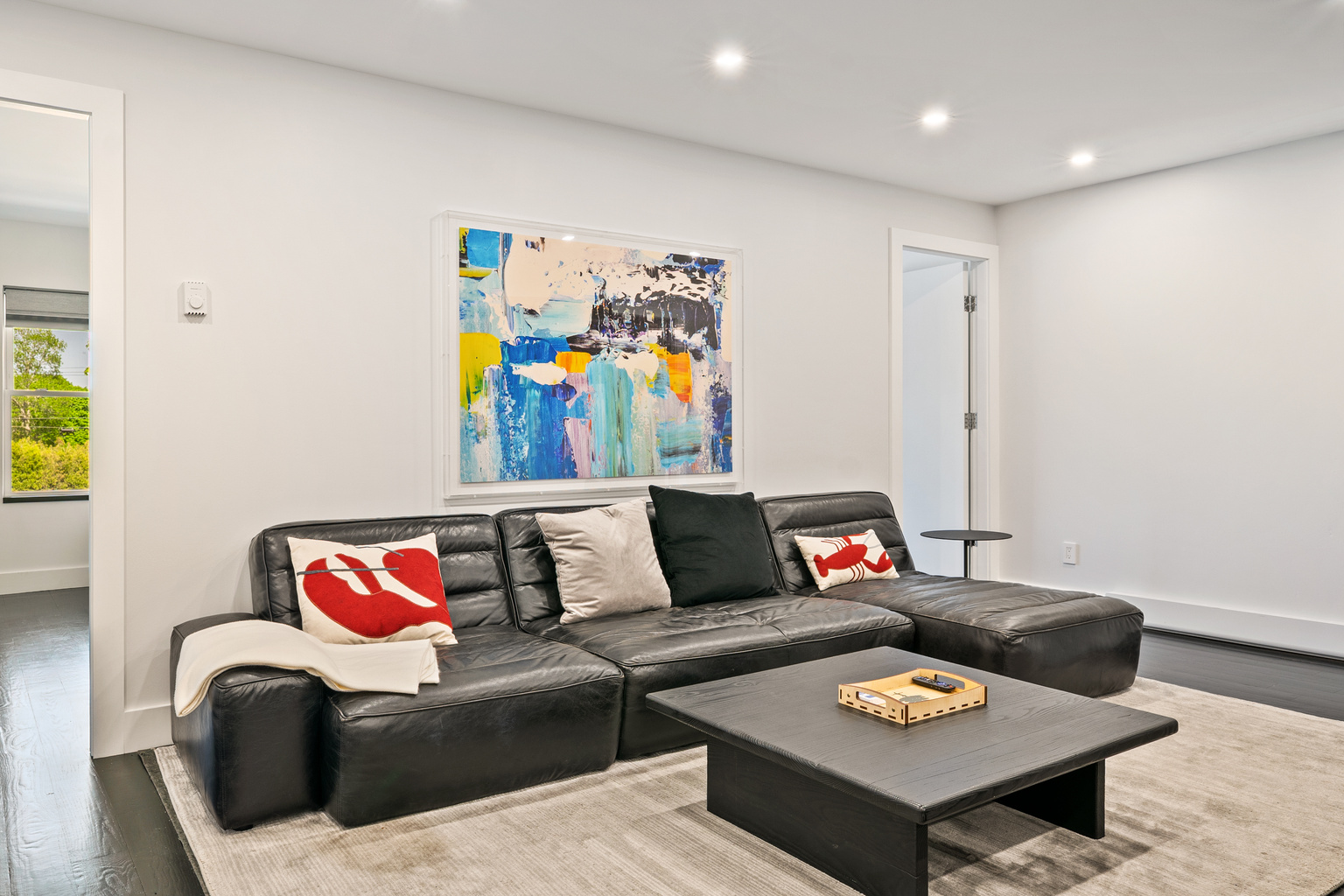 Sophisticated living area featuring a modern leather sectional, curated art, and full climate control via a wall-mounted AC/heat pump. Relax with the 55 Inch Roku smart TV (off-camera) in this open-concept hub in the heart of downtown Bar Harbor.