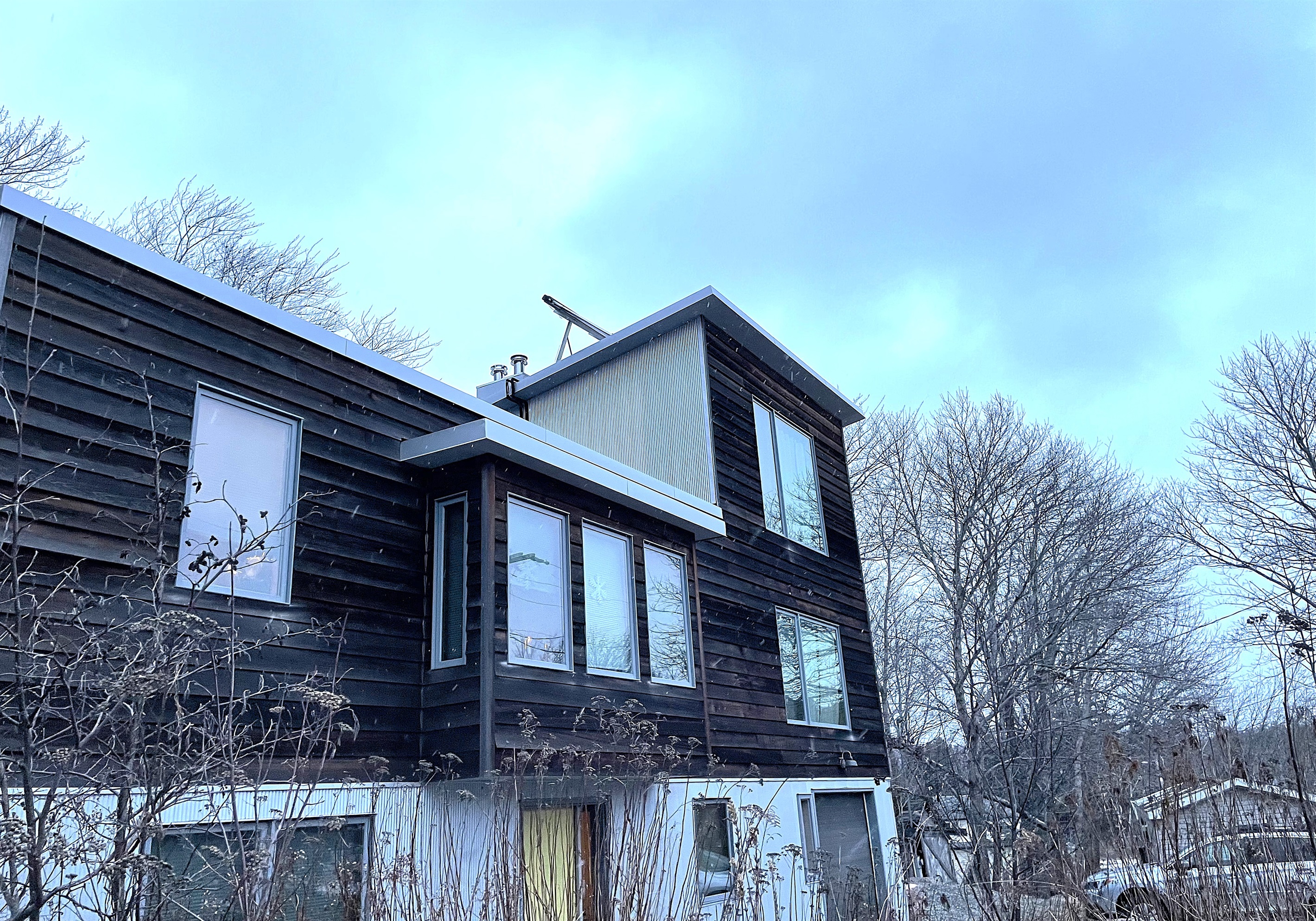 Bold architectural exterior of The Crag in the heart of Otter Creek village. Located just steps from the iconic Acadia Hot Showers and local general store, this modern retreat serves as your private backdoor entrance to Acadia National Park.
