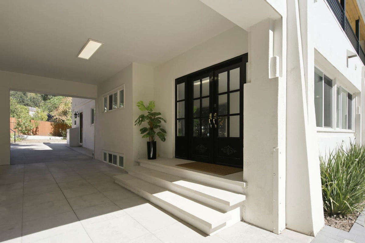 View of the entrance and covered passage framed by greenery visible beyond the property.