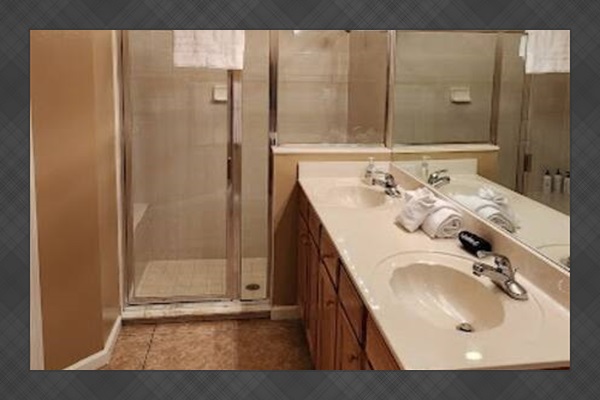 Spacious bathroom featuring a large vanity, tile shower, and clean neutral finishes.