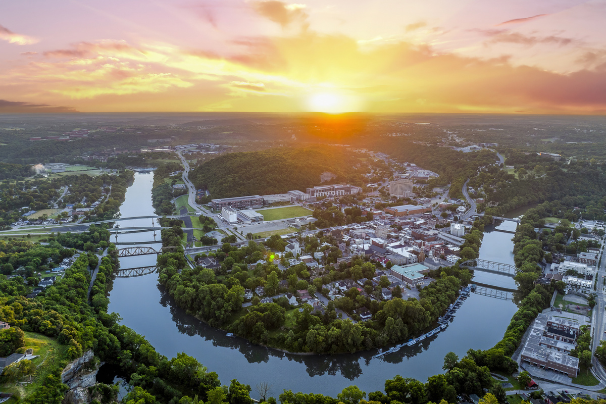The Kentucky River curves through Frankfort at golden hour, framed by limestone cliffs and rolling green hills.