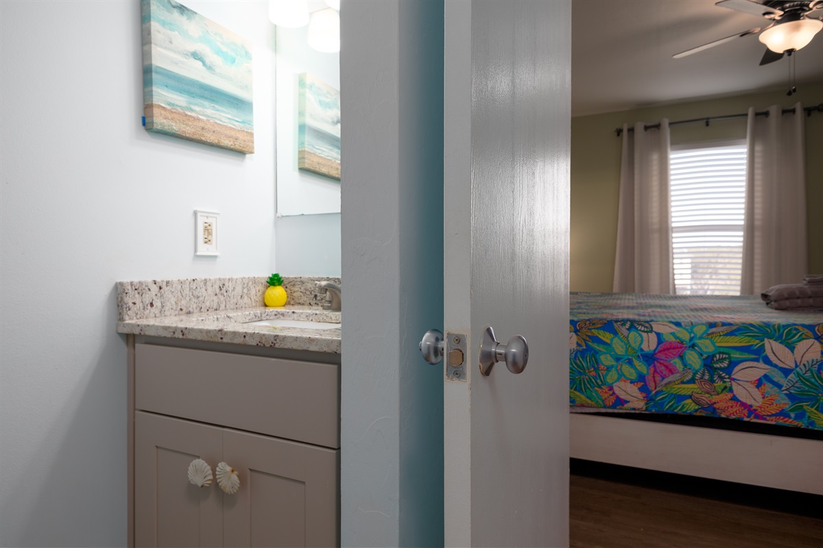 Bedroom-adjacent bathroom 2, featuring a granite vanity and coastal artwork