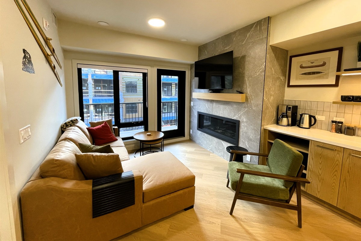 Living room with a leather sofa, gas fireplace, 55" TV, spacious balcony, it is open to adjacent kitchen area. The large sofa fold out queen sofa bed, linens are provided. Mountain decor compliments the room. 
