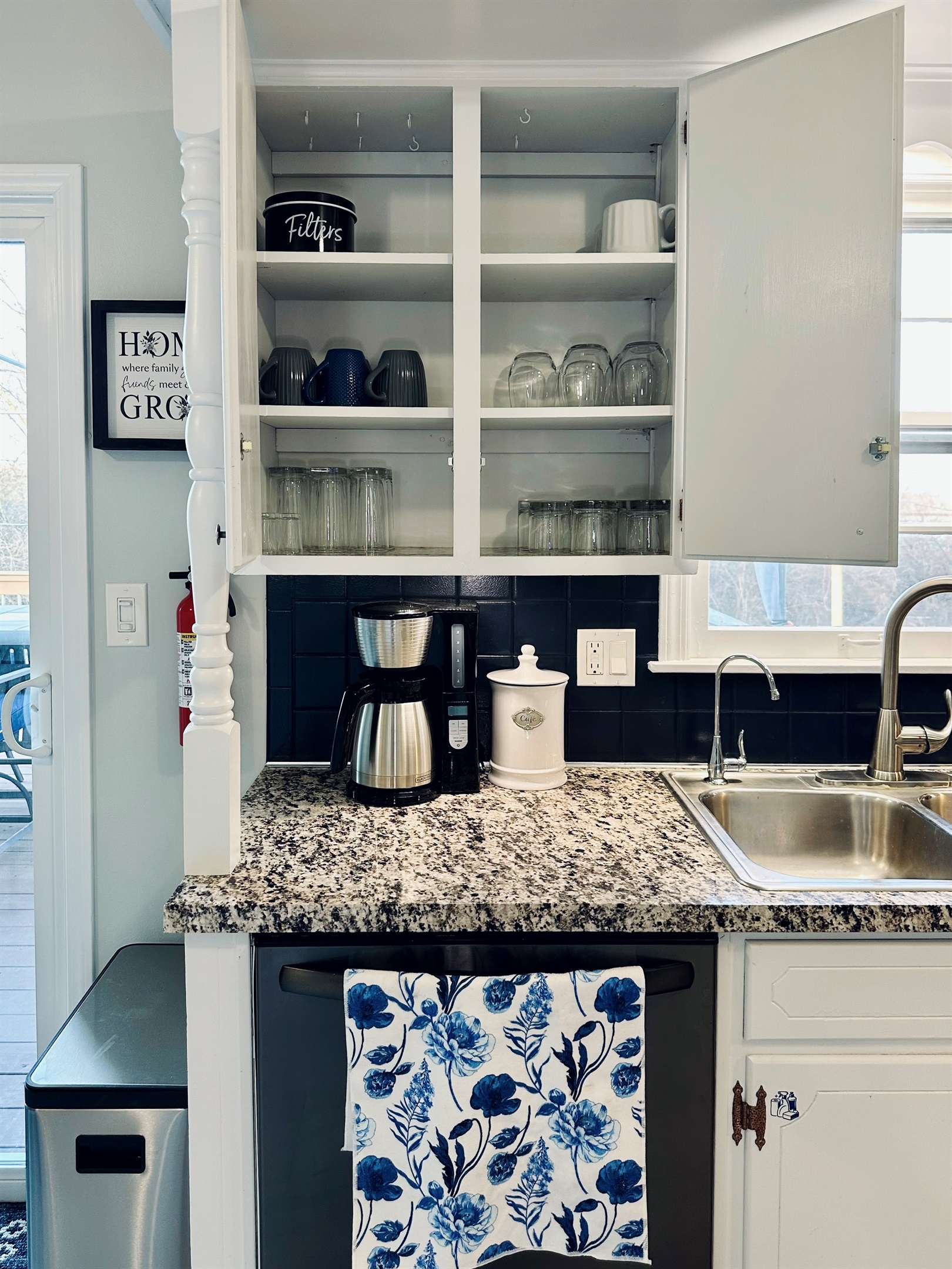 Coffee station featuring a coffee maker and organized coffee storage. Cabinets include coffee filters, mugs, wine glasses, tall drinking glasses, short glasses, and shot glasses—fully equipped for morning coffee and daily needs.