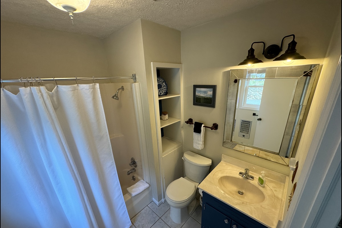 This main floor full bathroom has a tub/shower combo w/ curved shower rod & recently got an update! It's inside the front door so hot tubbing is easier & across from Main Floor King Bedroom