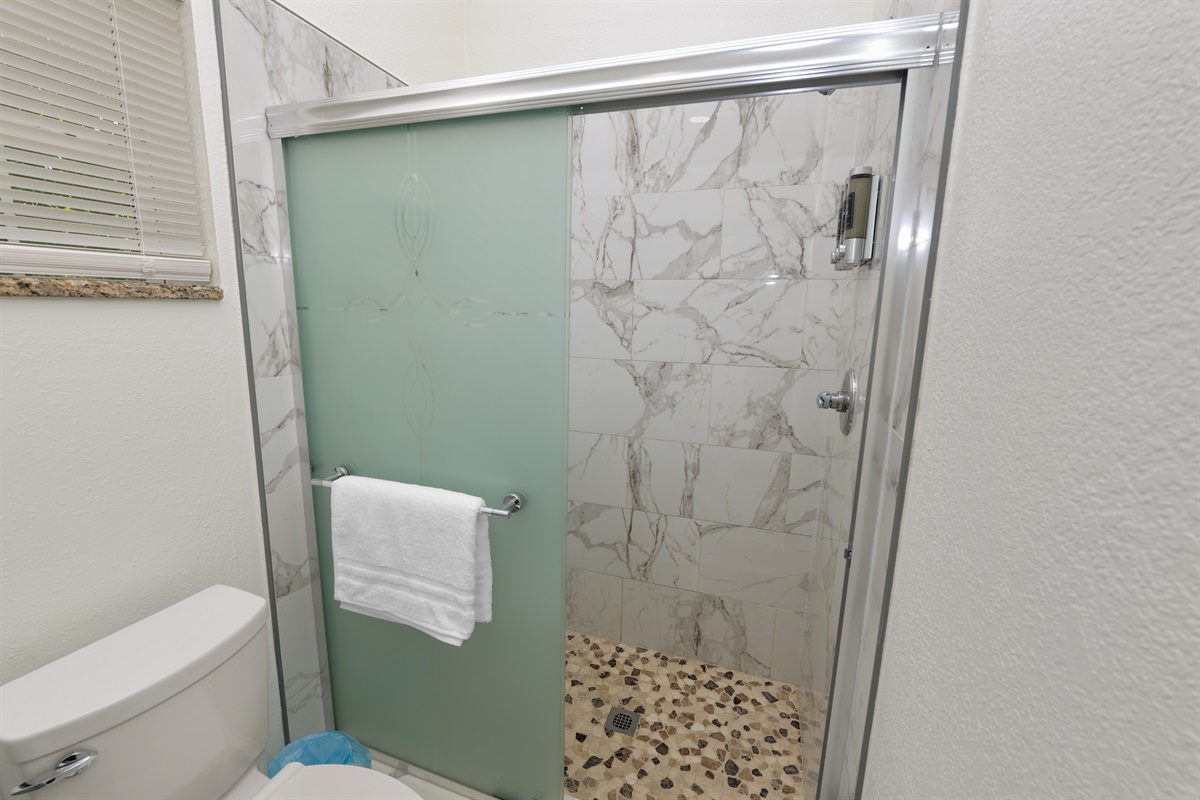 Start and end your day in comfort with this bright and pristine bathroom—highlighted by a luxurious rain-style shower, rich marble finishes, and hotel-quality amenities.