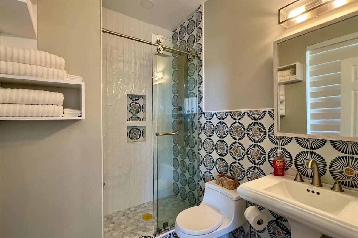 A pedestal sink with brushed nickel fixtures, wall-mounted towel storage, and a clean white toilet ensure convenience