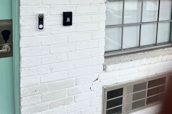 Entry detail with doorbell camera and Brinks access panel beside the front door.
