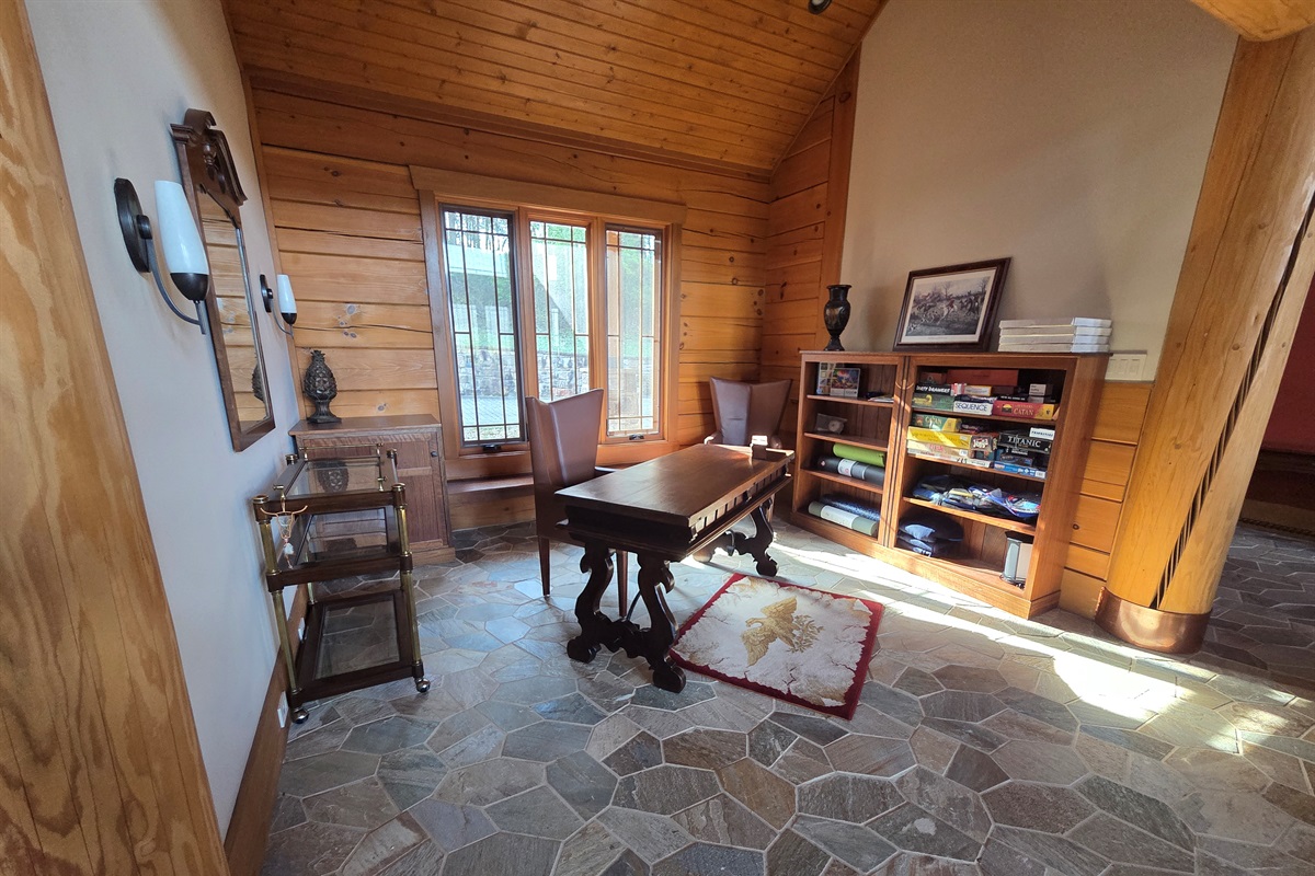 A versatile office space featuring a desk and shelves stocked with games, perfect for remote work or family fun. 