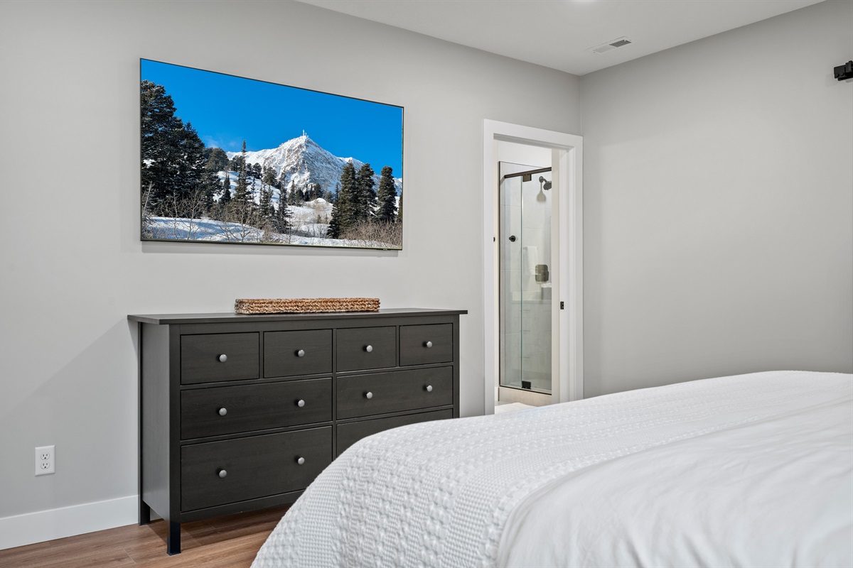 Large smart TV for streaming movies, spacious dresser, and private ensuite bath.