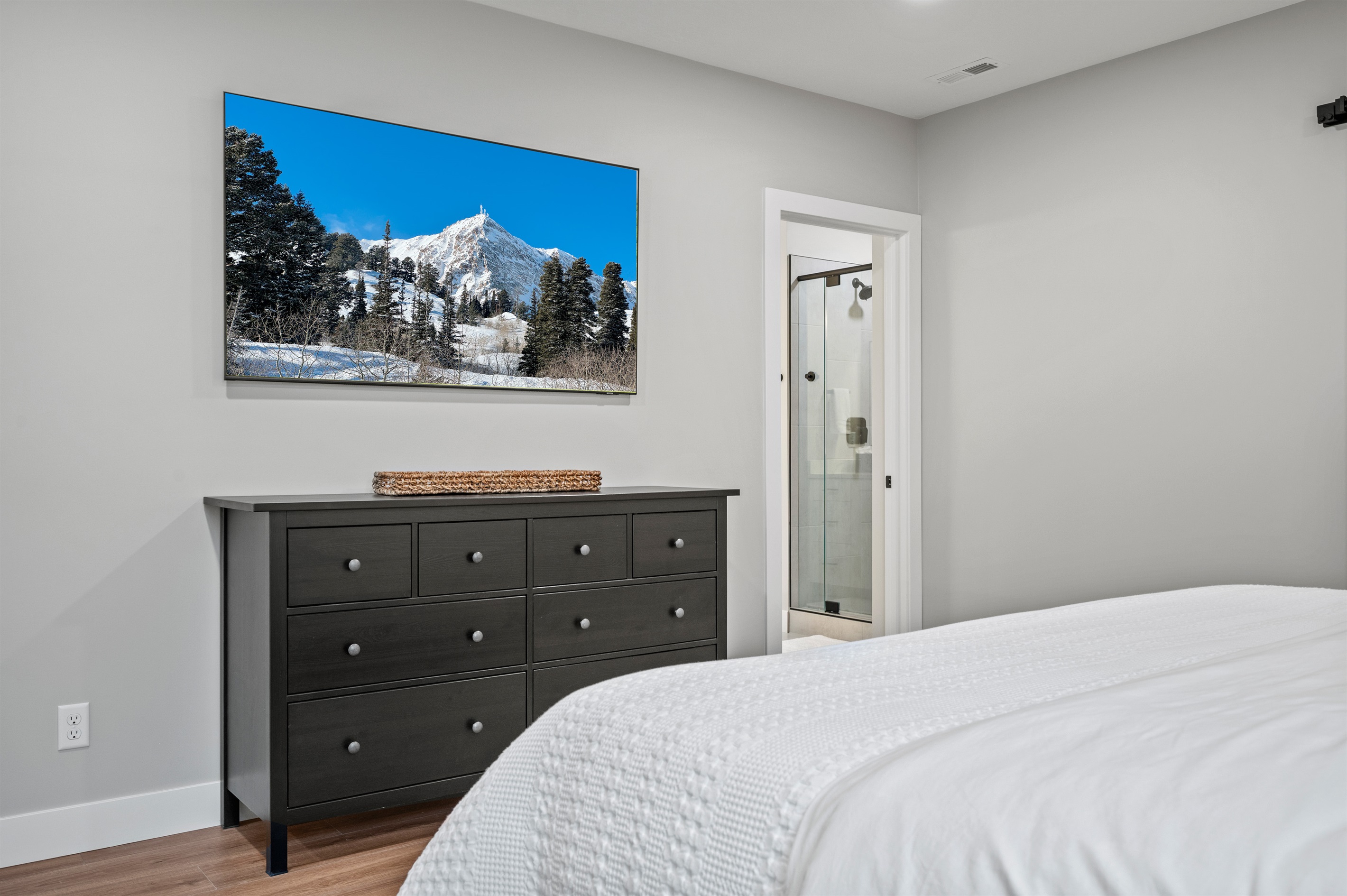 Large smart TV for streaming movies, spacious dresser, and private ensuite bath.