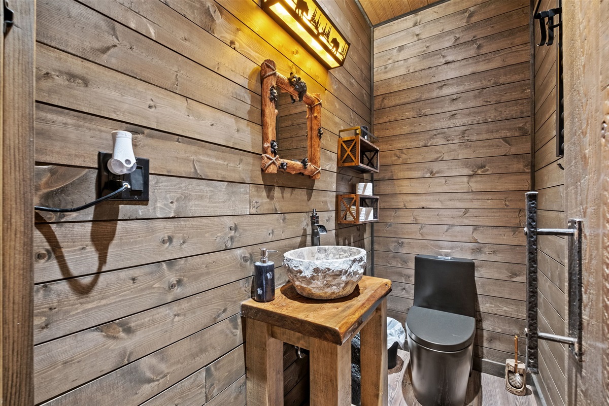 Cozy rustic powder room with wood paneling, artisan stone bowl sink, and custom bear-themed décor.