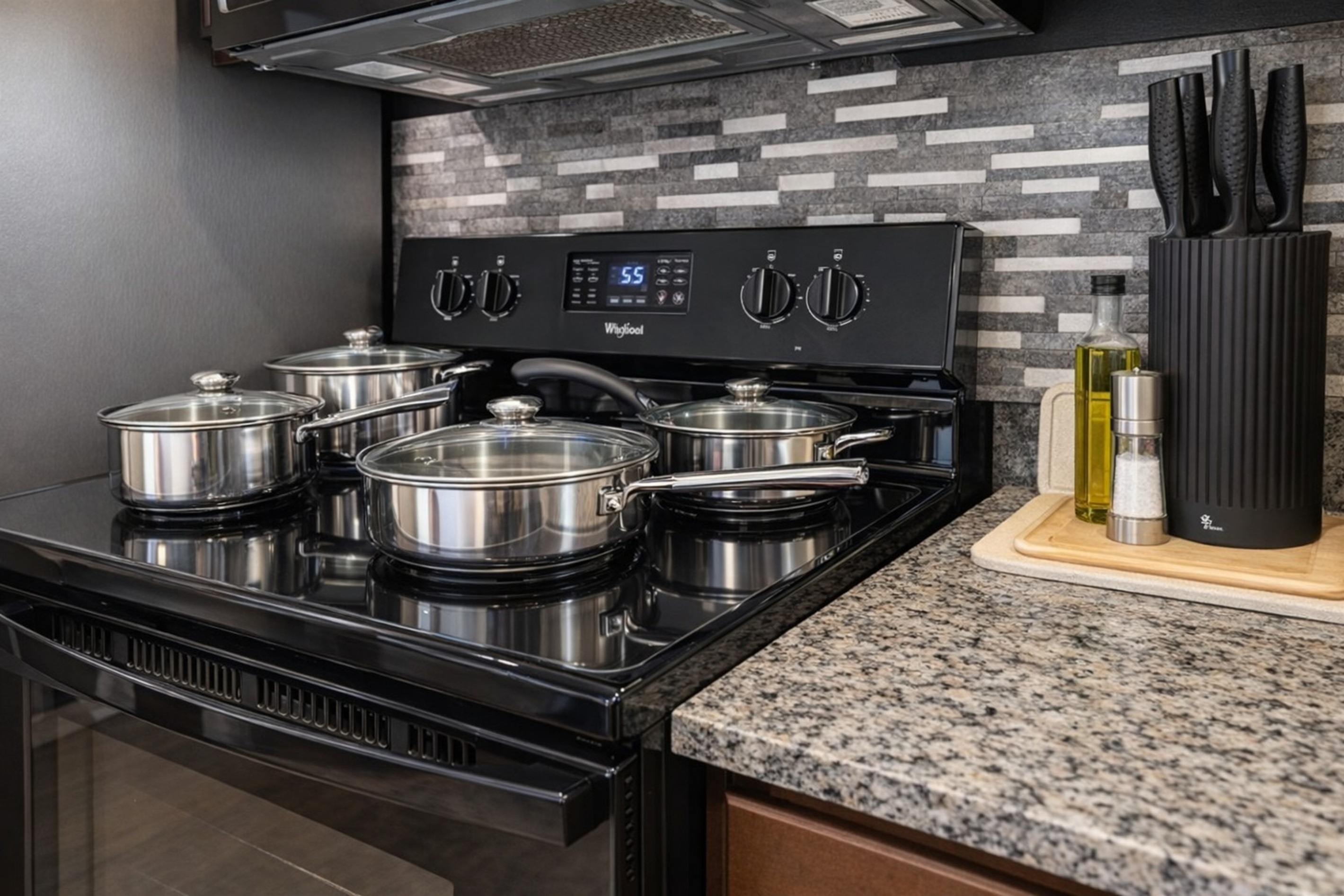 Modern kitchen stove with stainless steel cookware and granite countertops