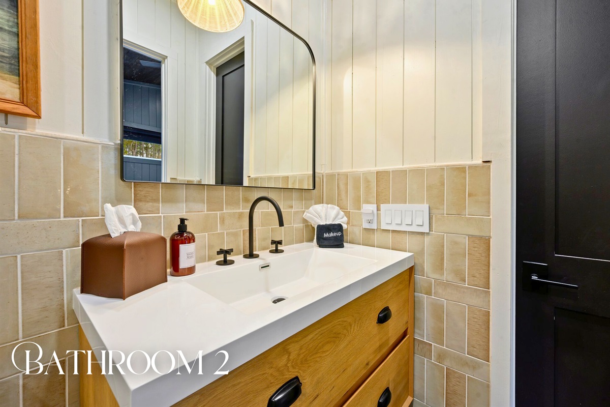 Another bathroom features fresh tilework, a sleek vanity, and a bright, modern feel
