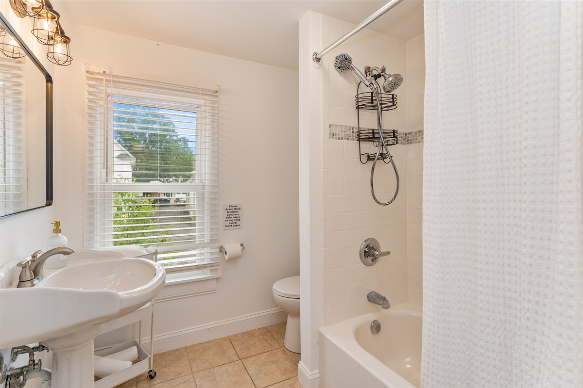 Bright and spotless bathroom with a deep soaking tub, rain showerhead, and window views. Full bathroom upstairs 