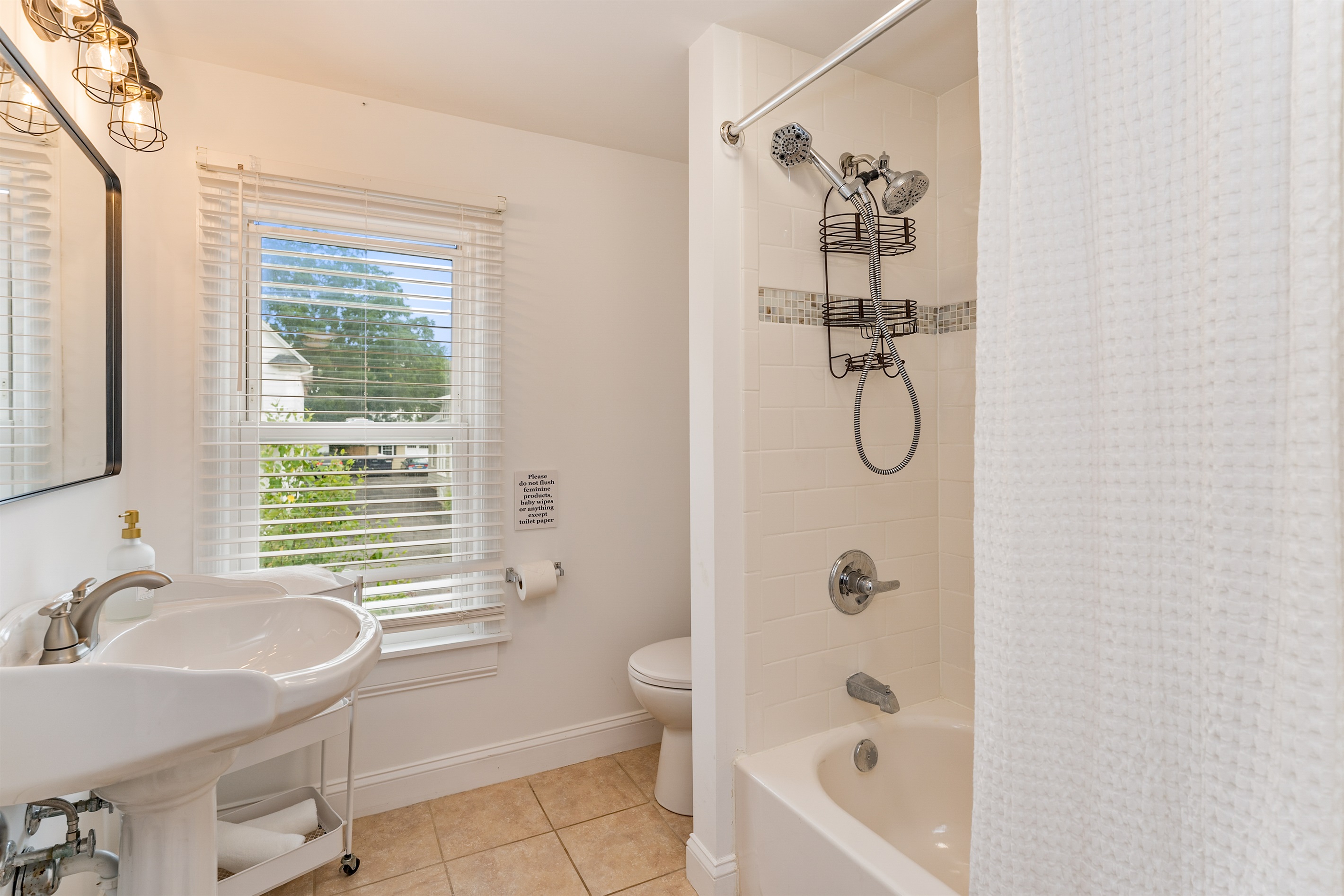 Bright and spotless bathroom with a deep soaking tub, rain showerhead, and window views. Full bathroom upstairs 