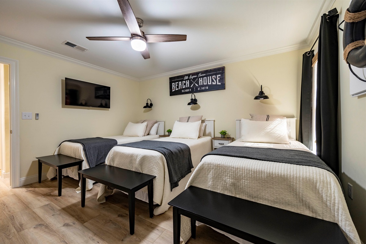 Cozy beach house bedroom with three beds, nautical decor, and relaxing vibes.