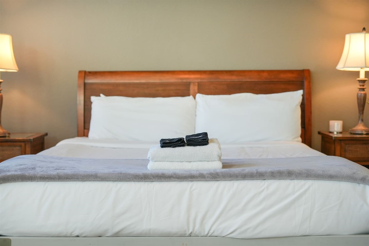 Plush king bed with fresh linens and bedside lighting.