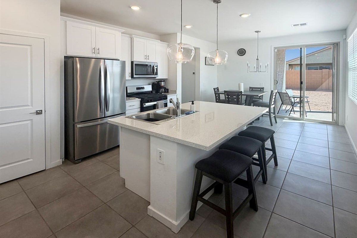 Kitchen with island, stools, stainless fridge, and microwave