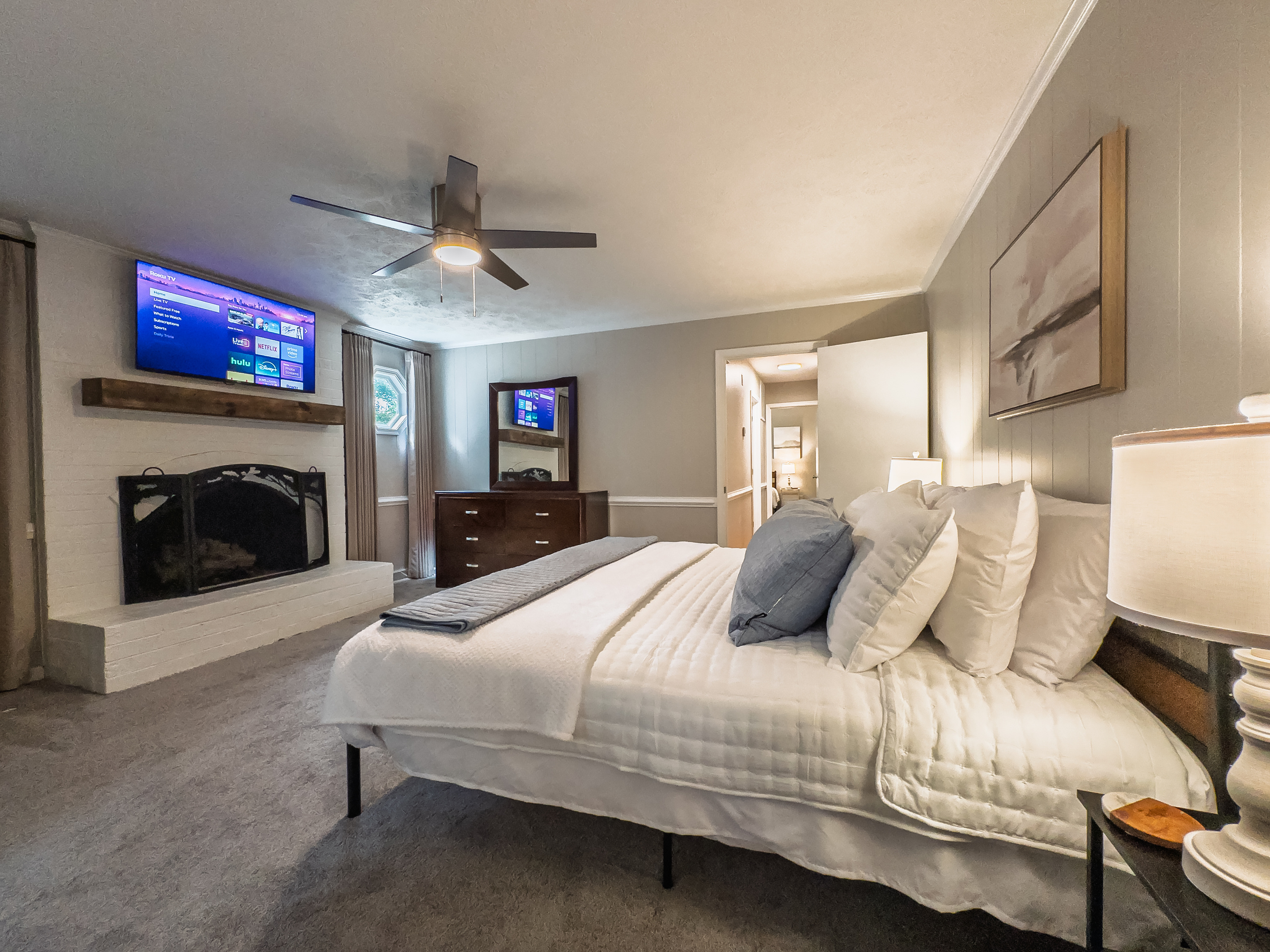 King bed, 55" Smart TV, ceiling fan, two led light nightstands with multiple charging ports, two multi light function lamps, blackout curtains, dresser, wardrobe closet, full length mirror, stylish brick fireplace - not in use.