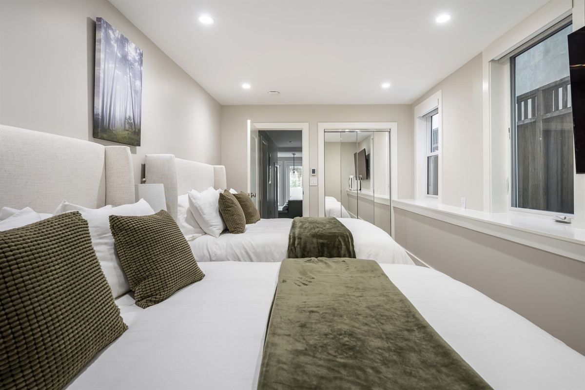 Large bedroom w/ 2 brand new Avocado Green queen beds & luxury bedding, 3 nightstands w/ built-in charging stations, built-in closet for storage & 65" NeoQLED 4k smart TV