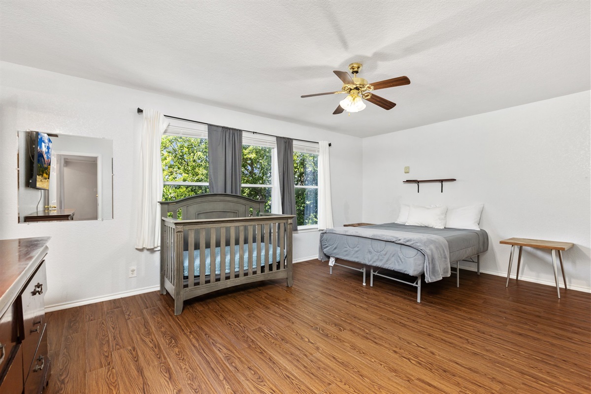 Primary suite with crib available for families with infants. Ceiling fan, hardwood floors, clothing storage, and comfortable bedding. This Northeast San Antonio home is set up for families of all sizes.
