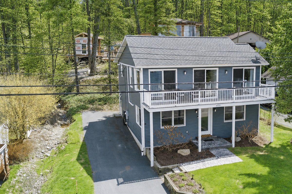Inviting lake retreat with a full-width balcony, bright exterior, and peaceful wooded backdrop—ideal for relaxing getaways and wine trail adventures! 🌳🍷☀️