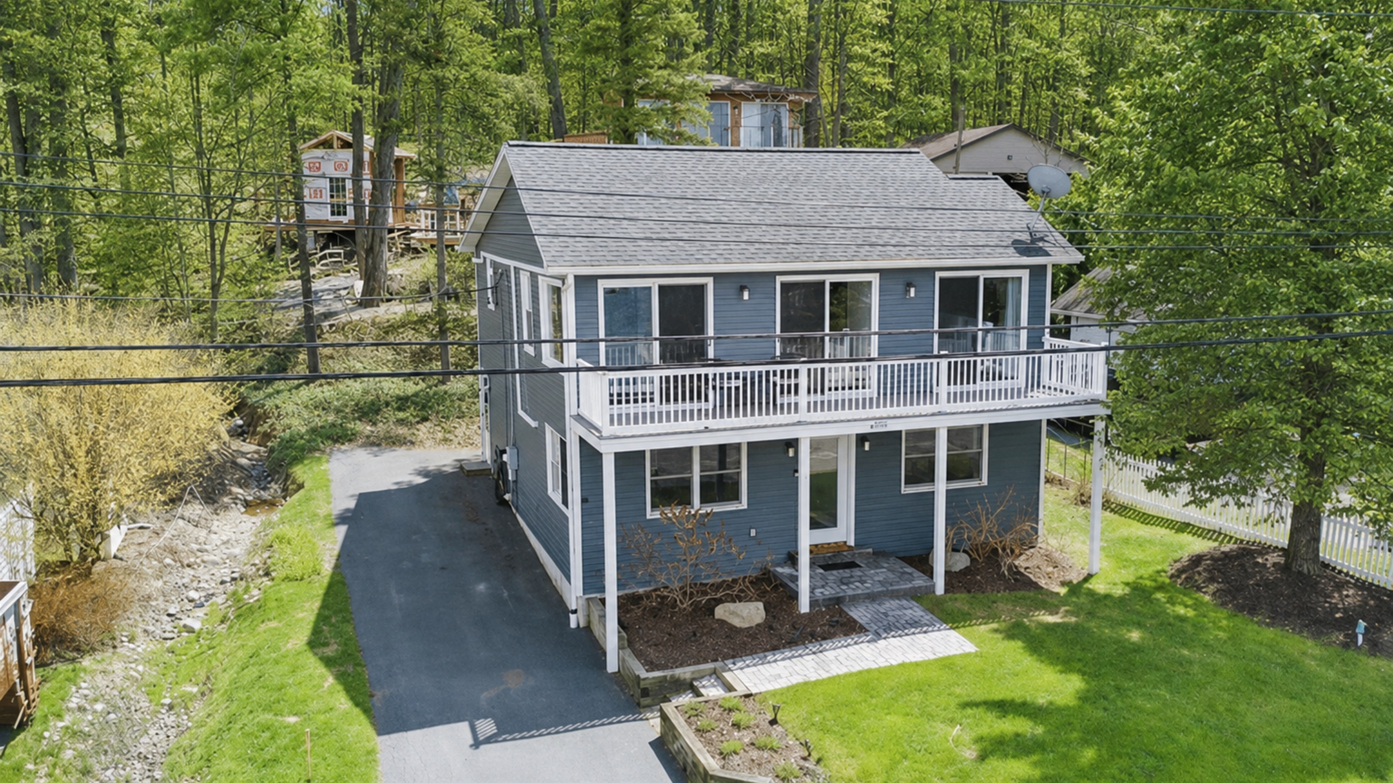 Inviting lake retreat with a full-width balcony, bright exterior, and peaceful wooded backdrop—ideal for relaxing getaways and wine trail adventures! 🌳🍷☀️