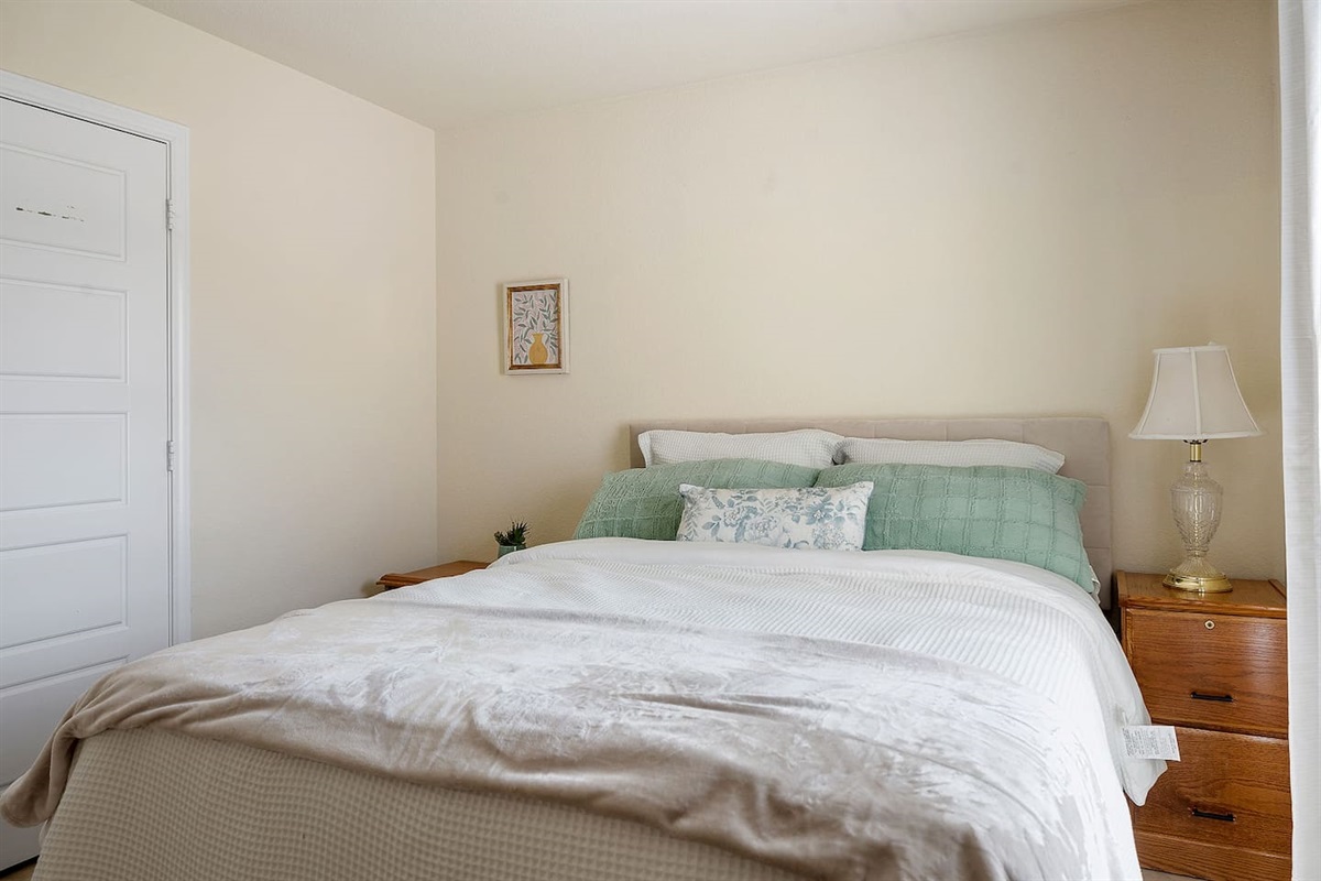 Enter this quaint bedroom with its gorgeous wall art, bedside lamp, and comfortable bed.