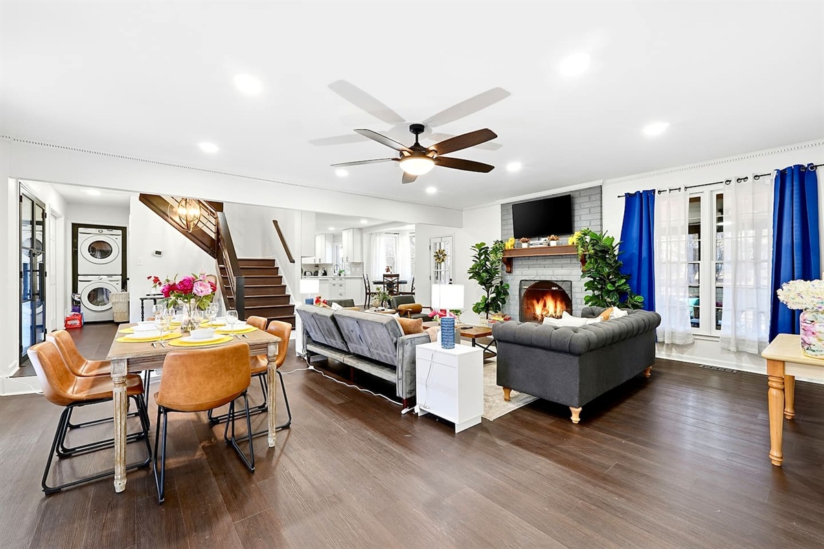 Warm and welcoming living room with two comfortable couches, two chairs, indoor plants, a cozy fireplace, and a TV powered by Google TV. Conveniently located as you walk through the front door and straight ahead from the primary side entrance. 