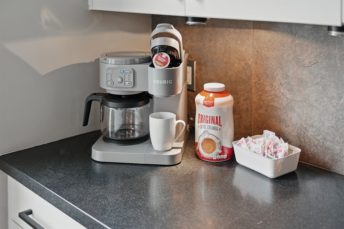 Start your day right with a Keurig dual coffee maker, mugs, creamer, and sweetener—all ready to go at your personal coffee station.